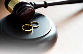 judge gavel with two wedding rings, symbolizing a divorce